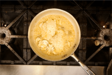 Chicken and mushrooms in a creamy champagne sauce simmers on the stove. Step five in the Champagne Chicken recipe shared by the chefs at Fire and Ice Restaurant as one of their local Vermont recipes made with Monument fresh local heavy cream.