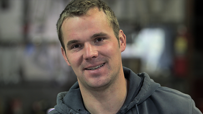 Ben James a young man in his thirties with short blonde hair smiles into camera, one of the team at Monument Farms Vermont Dairy Distributor