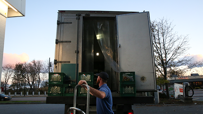 How is milk made? A young man loads crates of Monument fresh gallon milk jugs off the back of a truck.